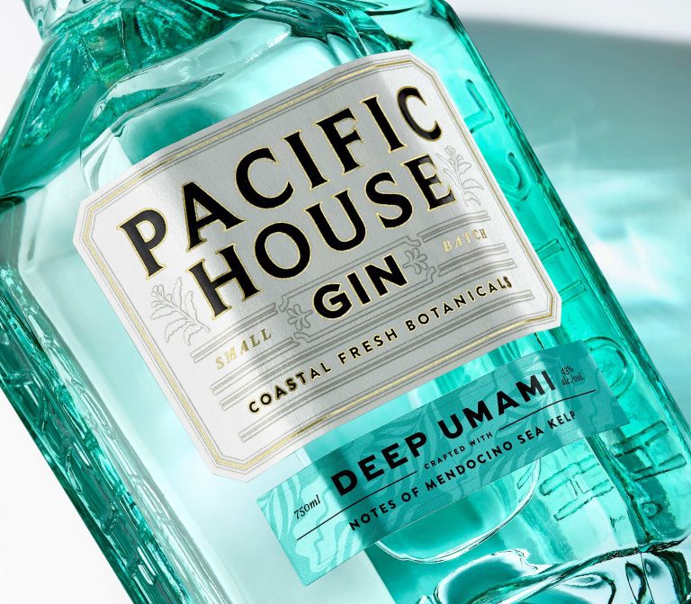 A coastal botanical gin bottle showcasing elegant branding and packaging, inspired by the deep blue Pacific Ocean. The bespoke glass design reflects the eight legs of an octopus, with facets resembling a precious jewel. The label design features oceanic elements, highlighting the unique character of this alcohol.